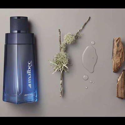 Frasco azul Malbec de O Boticário com elementos naturais ao lado