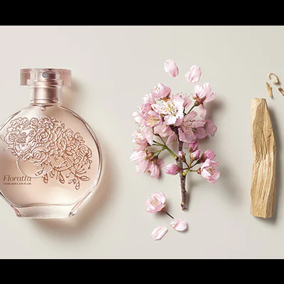 Frasco de perfume rosa, flores cor-de-rosa e pedaço de madeira sobre fundo bege