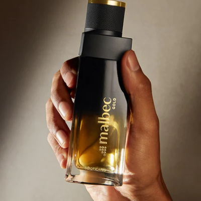 Frasco de perfume Malbec Gold da O Boticário em mão sobre fundo neutro