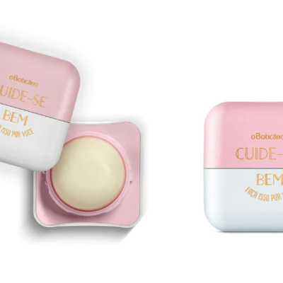 Embalagem de bálsamo rosa e branca com texto dourado, aberta com creme visível