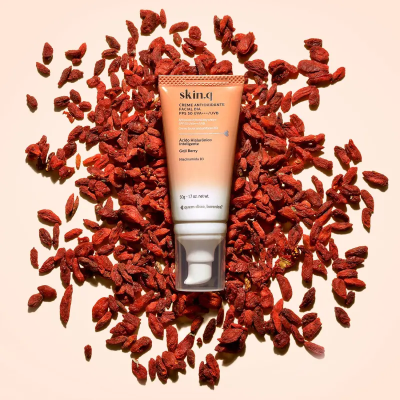 Tubo de creme hidratante Skin&+ colocado sobre bagas secas vermelhas