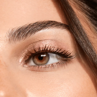 Close-up de olho castanho com sombra dourada e sobrancelha grossa
