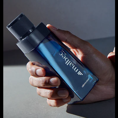 Frasco azul escuro de perfume Male e Blue da Malbec segurado por uma mão