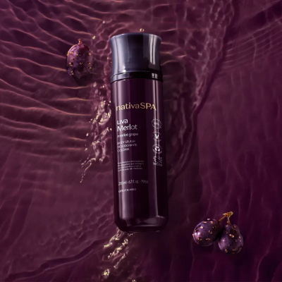 Frasco de cosmético nativaSPA uva Merlot sobre líquido roxo com uvas