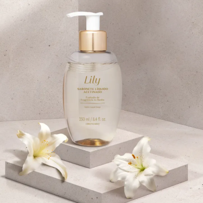 Frasco de sabonete líquido Lily transparente com tampa branca e dourada em bases de pedra bege com flores brancas
