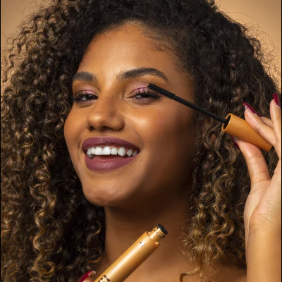 Mulher com rímel dourado aplicado nos cílios