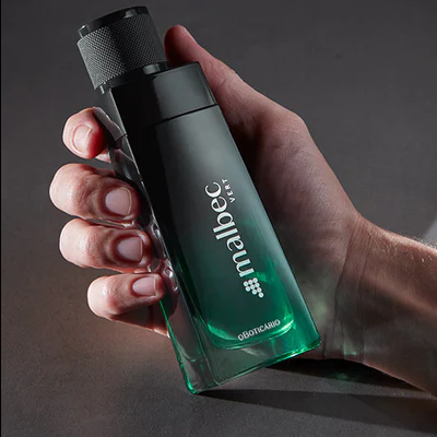 Frasco de perfume Malbec Vert verde e preto na mão sobre fundo cinza