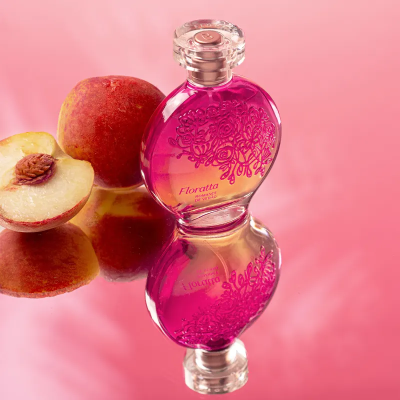 Frasco de perfume rosa com pêssegos em fundo rosa