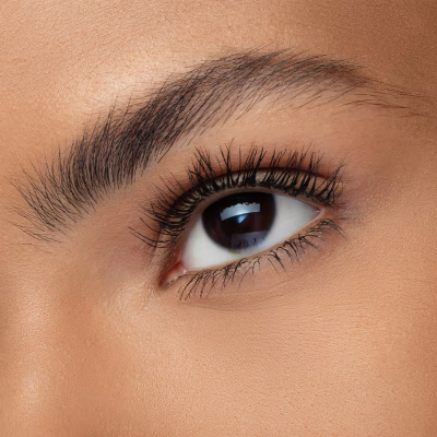 Close-up de um olho castanho com sobrancelha preenchida e pestanas longas.