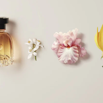 Frasco de perfume com três flores em fundo creme