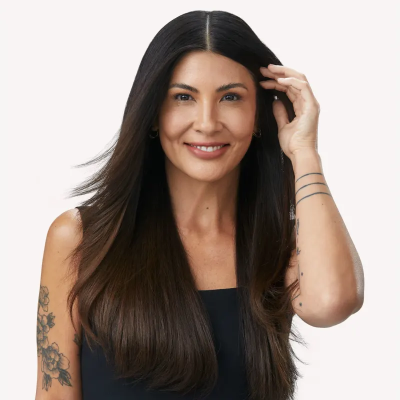 Mulher com cabelo comprido castanho escuro e top preto a sorrir