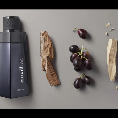 Frasco preto fosco com texto junto a madeira e uvas pretas