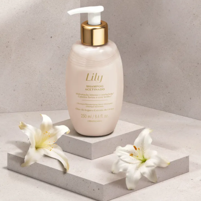 Frasco de shampoo acetinado Lily rosa com tampa branca e dourada sobre plataforma cinza com flores de lírio brancas