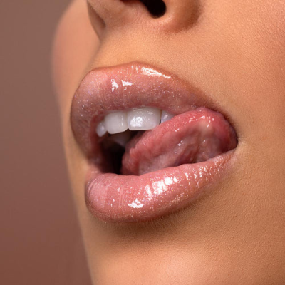 Lábios femininos com gloss rosa brilhante e língua visível