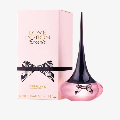 Frasco rosa de perfume com tampa preta longa e caixa rosa com laço preto e textos Love Potion Secrets Oriflame