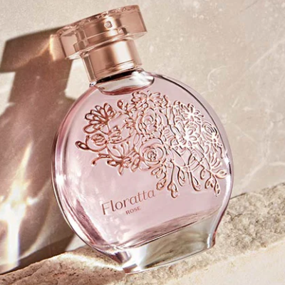 Frasco redondo de perfume rosa com padrão floral em relevo e tampa rosa dourada