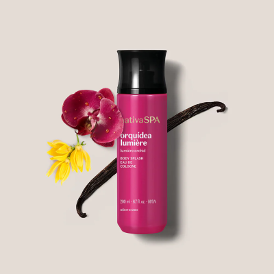 Frasco rosa de Body Splash com tampa preta e flores decorativas ao fundo