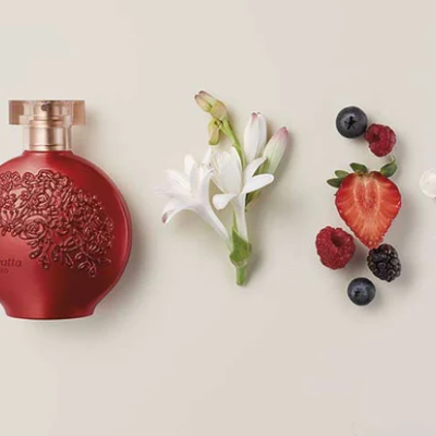 Garrafa de perfume vermelha com flores e bagas ao lado
