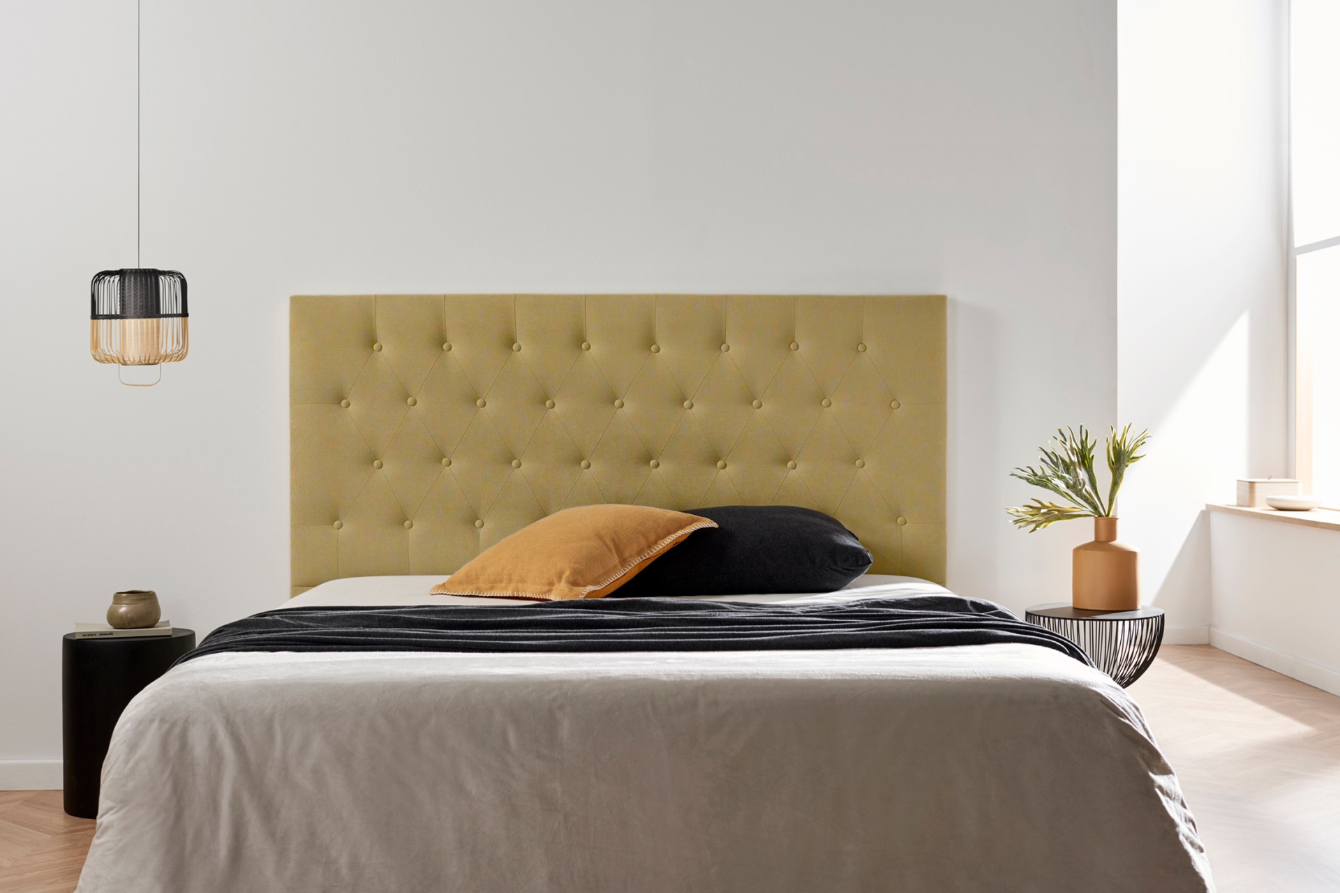 cama dupla com cabeceira verde-oliva estofada e botões, almofadas cor de mostarda e preta