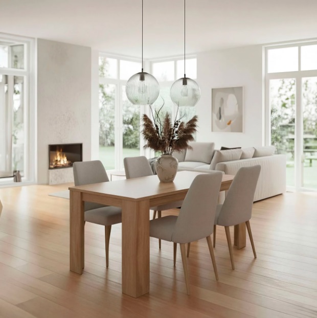 Mesa de madeira com quatro cadeiras cinza e duas lâmpadas suspensas em sala luminosa