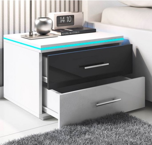 Mesa de cabeceira branca e preta com gavetas abertas e iluminação azul, relógio digital e objeto decorativo prateado em cima