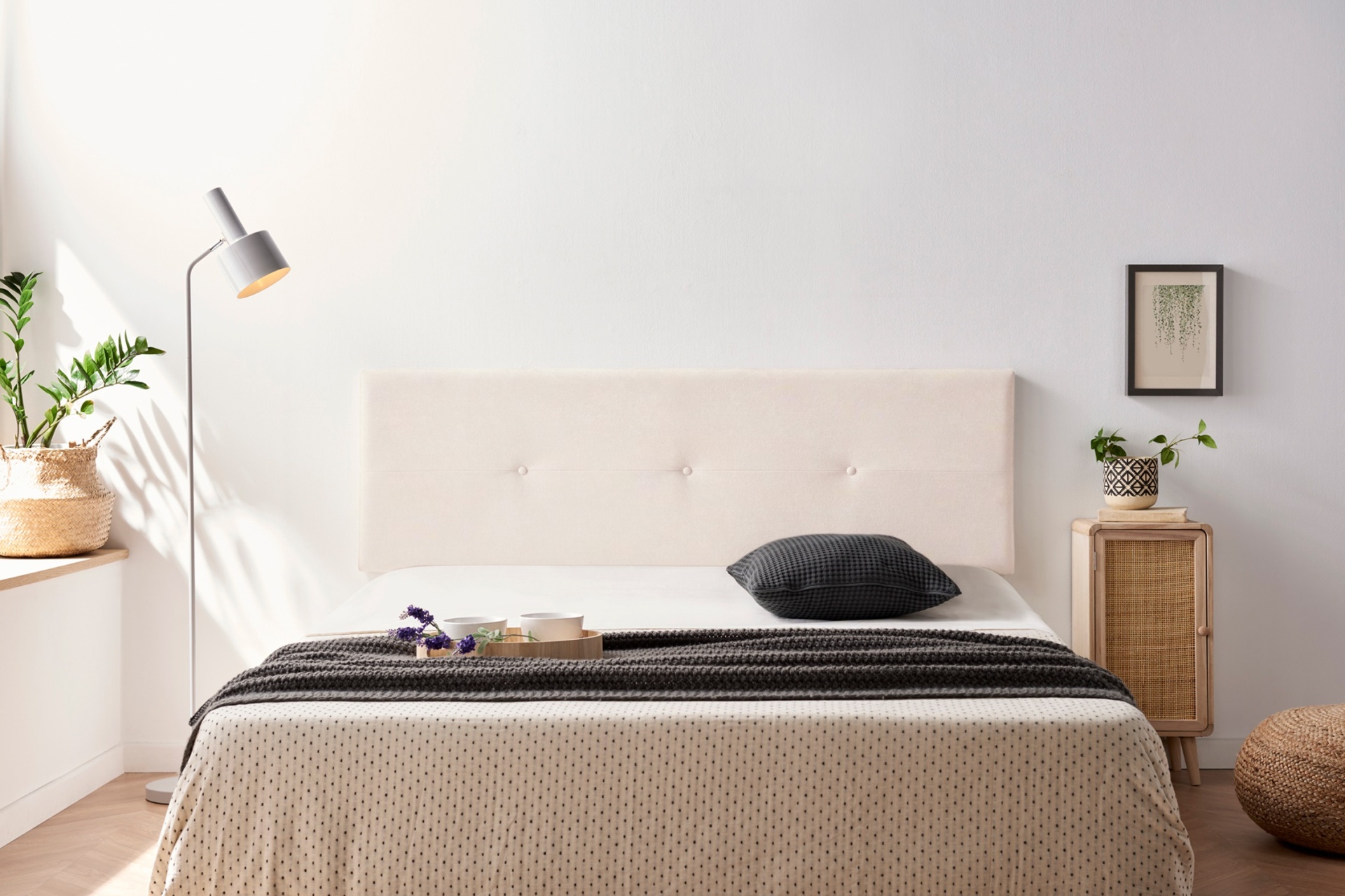 Cama estofada creme com roupa de cama bege e manta preta numa decoração de quarto minimalista