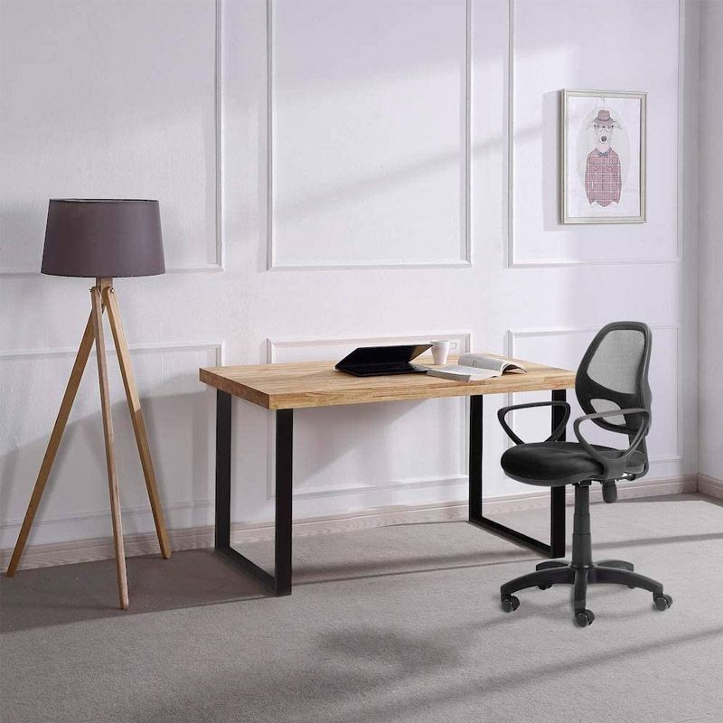 Escritório minimalista com secretária em madeira, cadeira preta, candeeiro de pé e quadro na parede