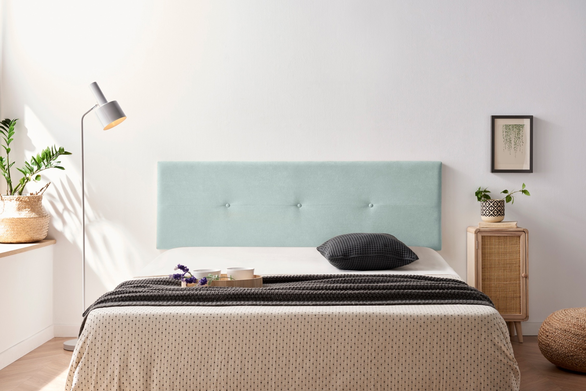 Quarto com cama, cabeceira azul claro, colcha bege com manta preta e decoração minimalista