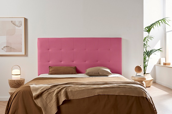 Cama com cabeceira rosa estofada e roupa de cama castanha num quarto moderno e minimalista