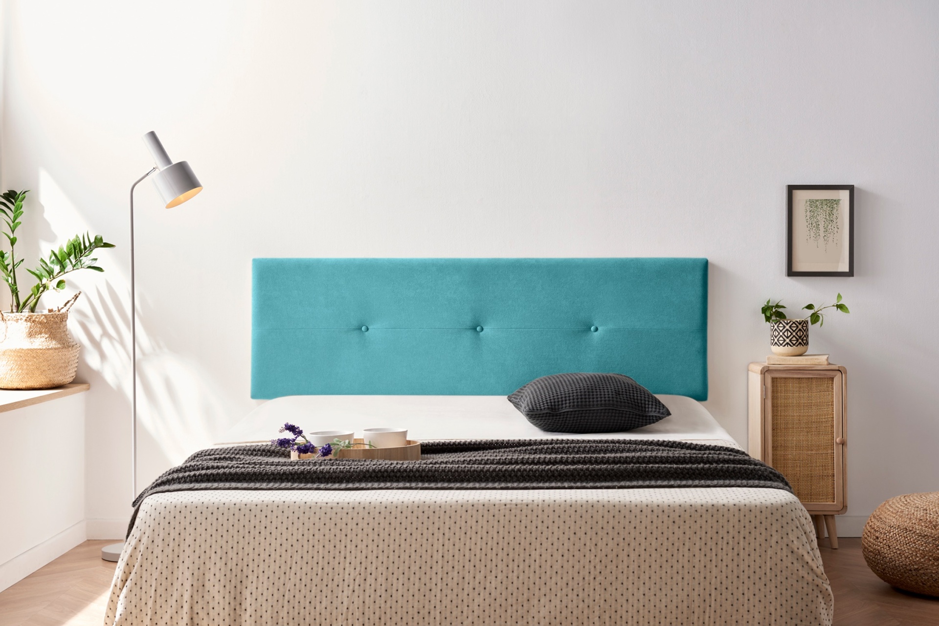 Cabeceira azul turquesa estofada numa cama com colcha bege e cinza num quarto minimalista