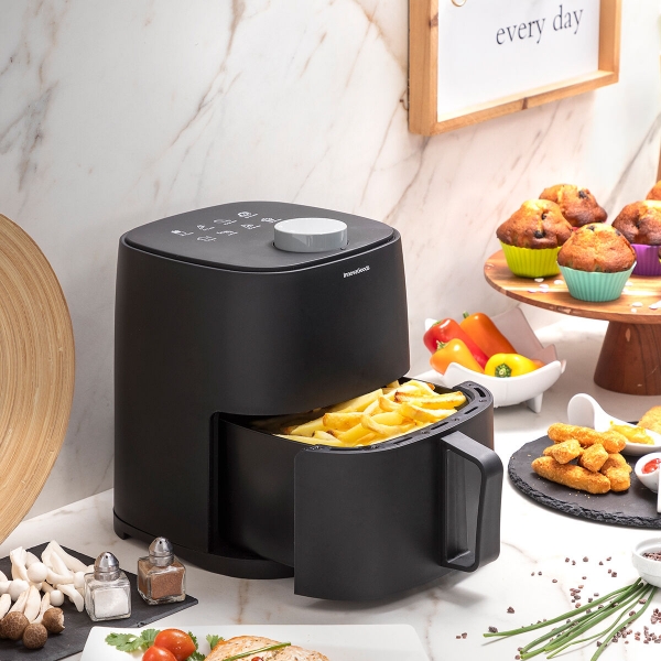 Máquina airfryer preta com batatas fritas numa cozinha moderna