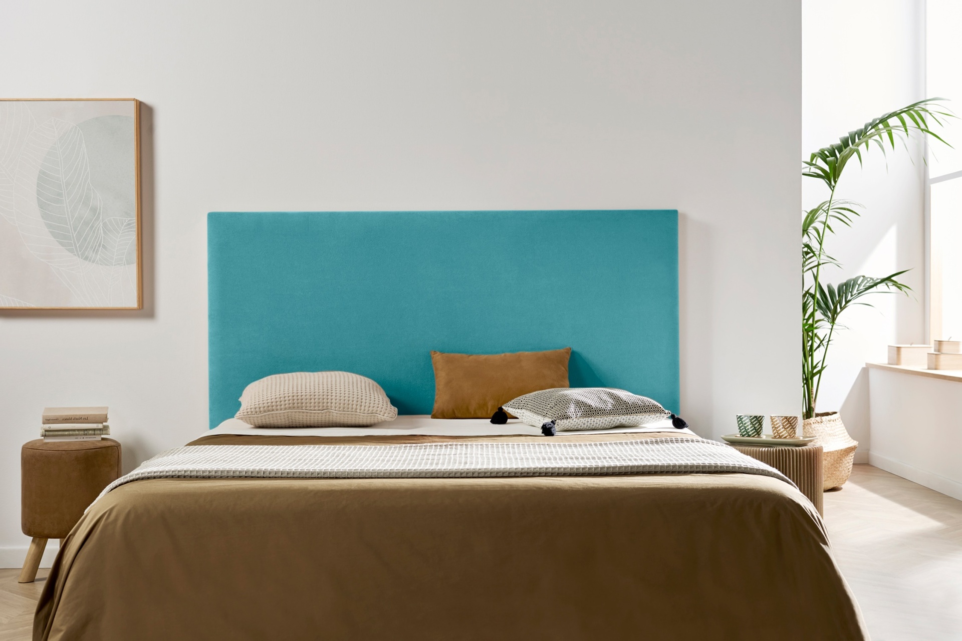 Cama com cabeceira azul-turquesa e roupa de cama castanha e bege, em ambiente minimalista