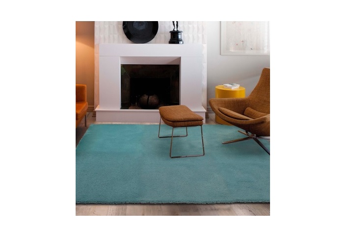 Tapete azul claro com poltrona castanha e lareira branca ao fundo