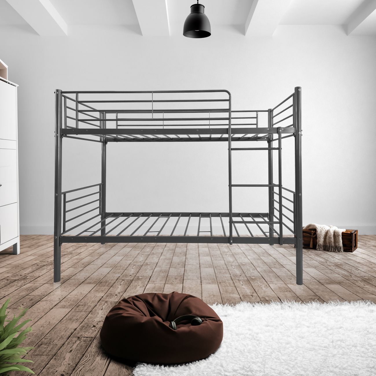 Cama beliche metálica cinzenta num quarto com chão de madeira, tapete branco e puff castanho