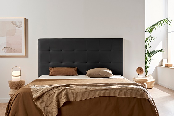 Cama com cabeceira preta, roupa de cama castanha, duas mesas de cabeceira com abajures e decoração minimalista