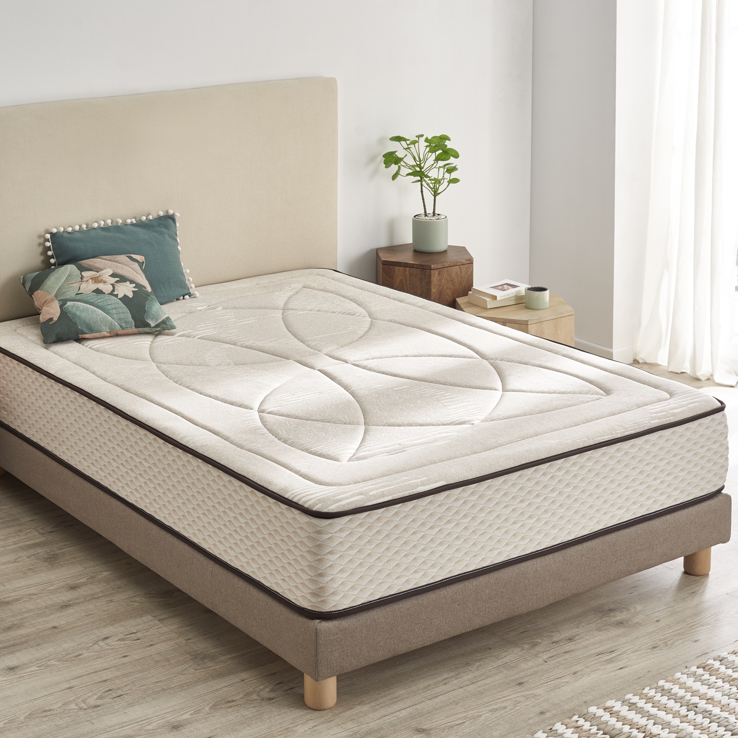 Colchão individual creme com padrão em cama cinza clara com pés em madeira e almofadas decorativas