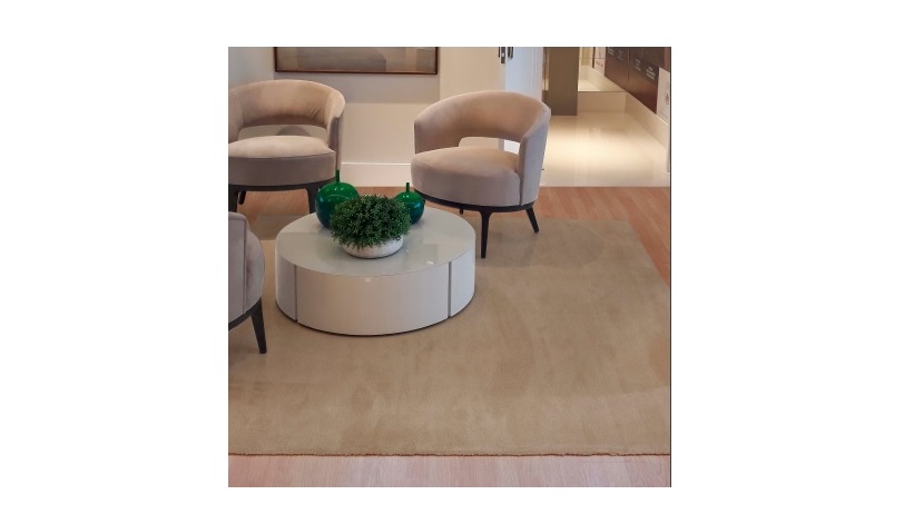 Sala com duas cadeiras bege, mesa redonda branca e carpete bege