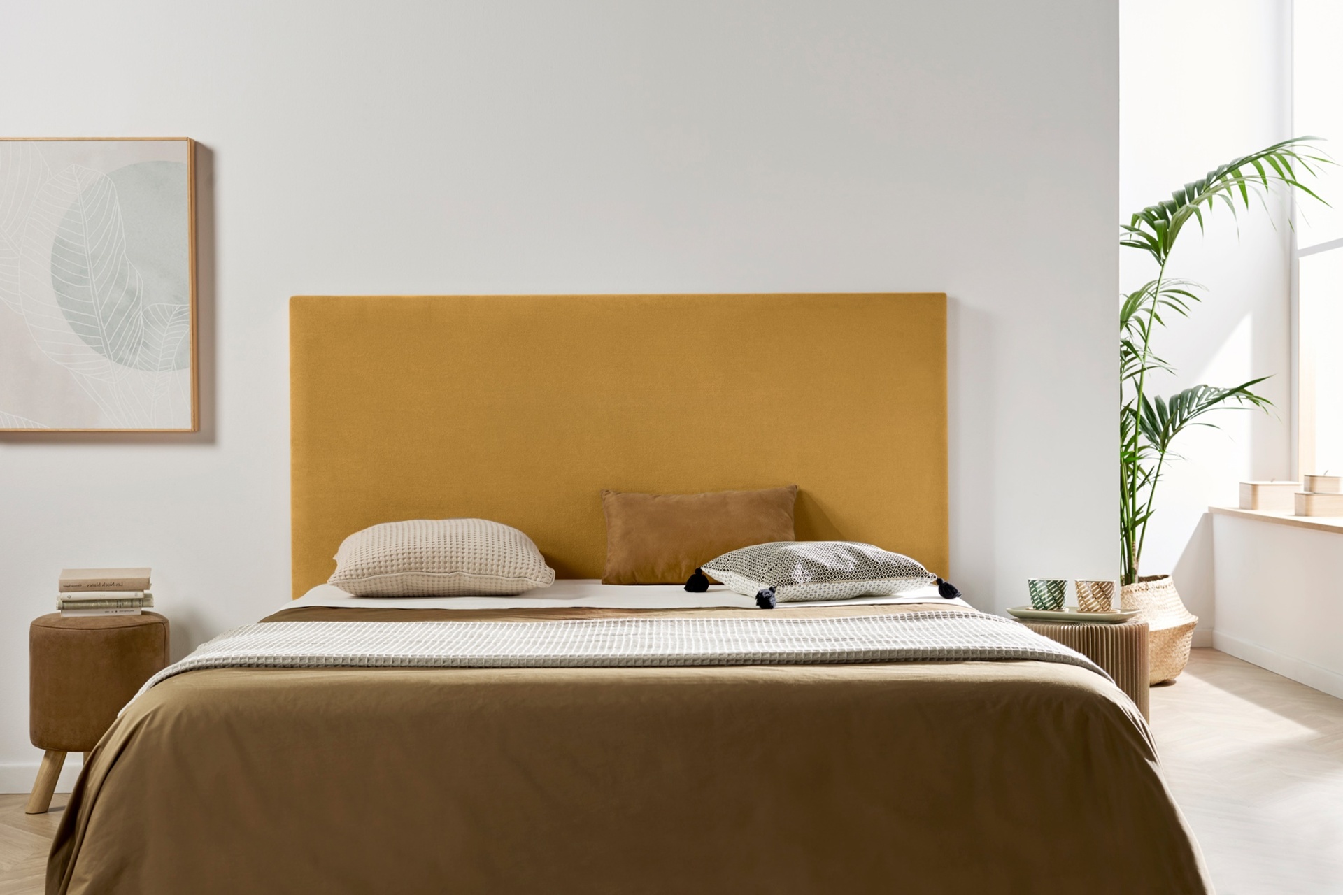 Cama com cabeceira amarela em quarto minimalista com móveis em madeira clara