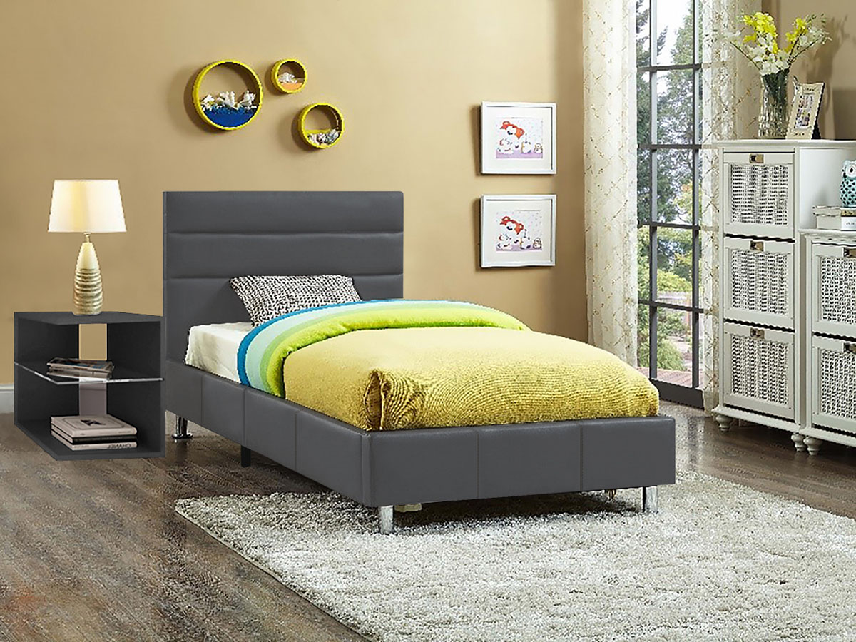 Cama individual cinza com roupa de cama verde e azul, mesa de cabeceira preta com candeeiro branco, tapete cinza, decoração de parede e armário branco junto à janela