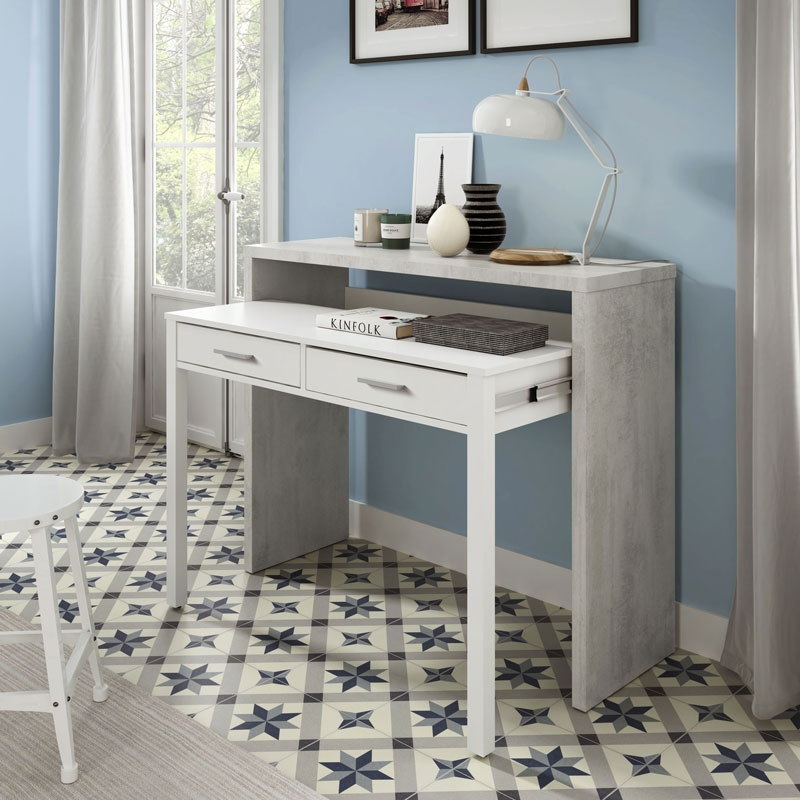 Secretária branca e cinza claro com decoração e candeeiro, em ambiente interior com parede azul e chão azulejado geométrico
