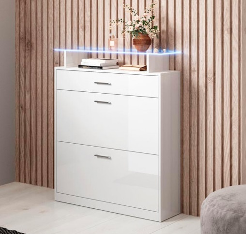 Aparador branco brilhante com três gavetas decorado com livros e vaso, contra parede de painéis de madeira.