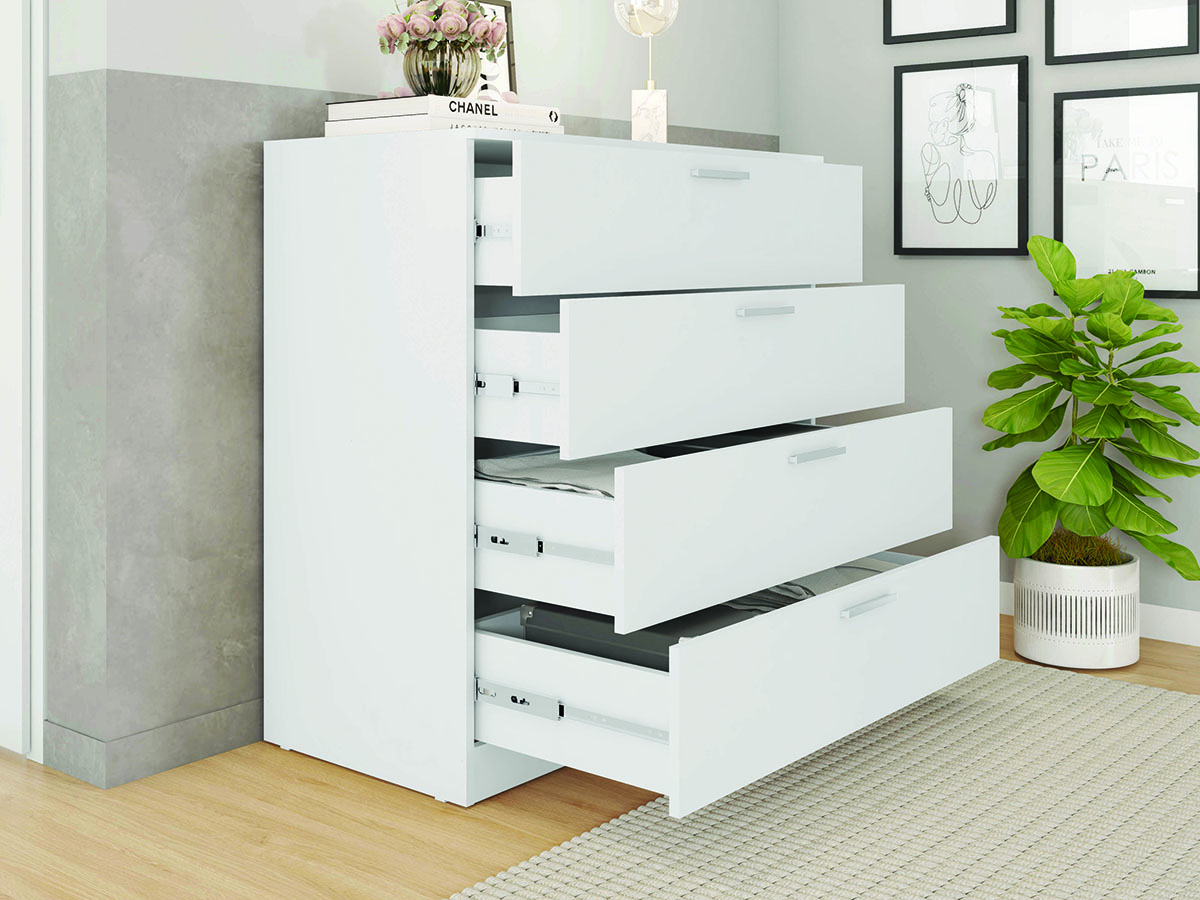 Cômoda branca com quatro gavetas abertas numa sala com planta e quadros na parede