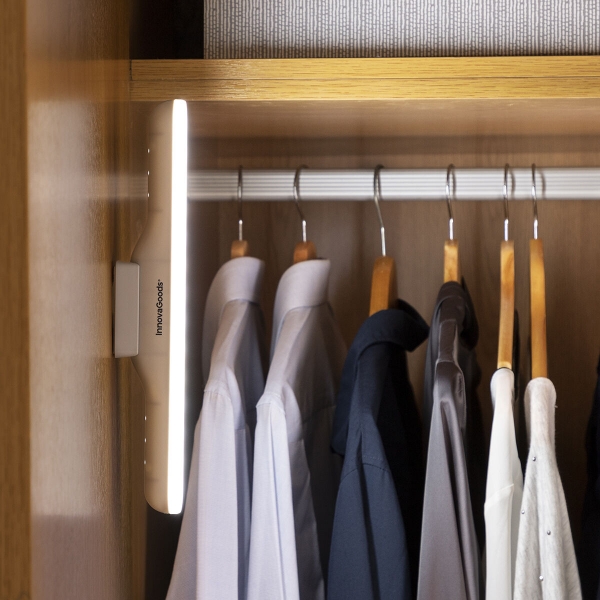 Camisas penduradas em cabides num armário de madeira iluminado