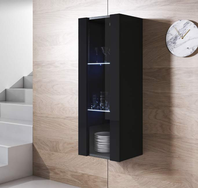 Móvel de parede vertical preto com porta de vidro, copos, taças e pratos em prateleiras, parede de madeira clara, escada branca e relógio redondo mármore