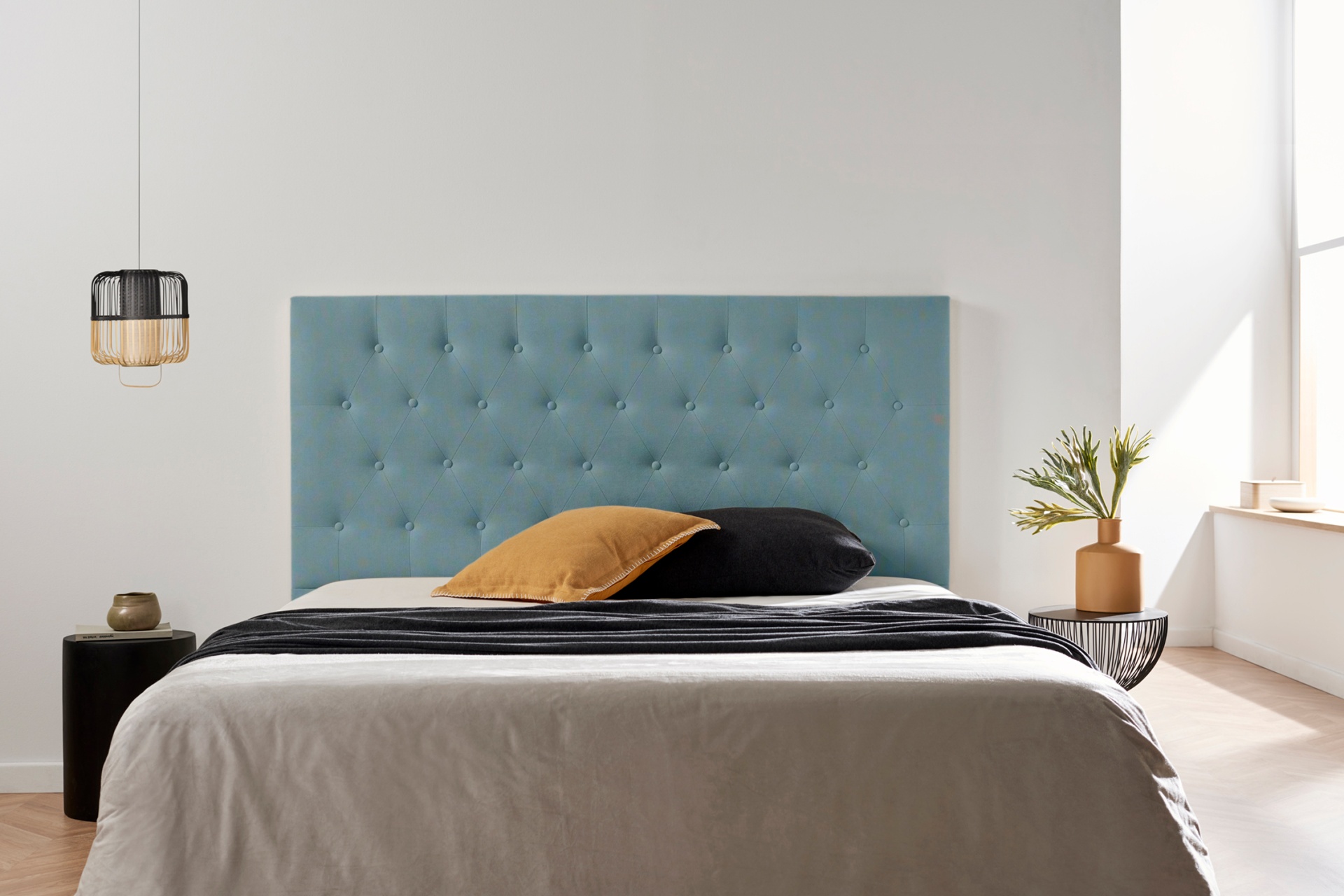 Cama com cabeceira azul estofada e decoração minimalista