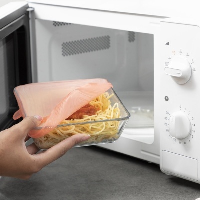 Micro-ondas branco com tabuleiro de vidro com massa coberto por silicone cor de pêssego