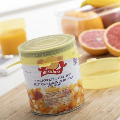 Lata de cocktail de frutas SAI com tampa amarela e frutas em fundo desfocado