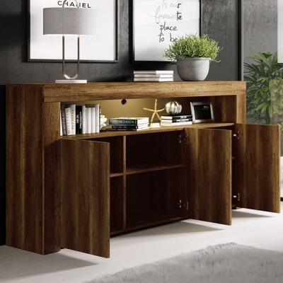 Aparador em madeira escura com portas abertas, livros e decoração, parede escura com quadros e candeeiro