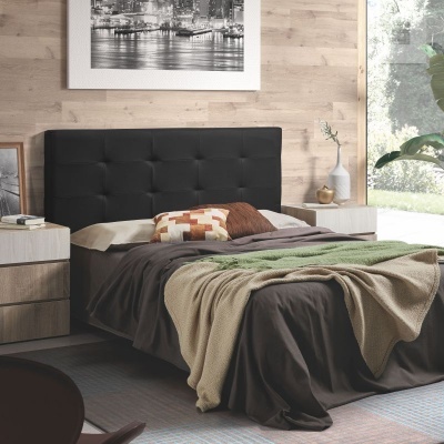 Cama de casal com cabeceira preta estofada e roupa de cama castanha com cobertores bege e verde, mesas de cabeceira de madeira clara e parede em madeira clara.