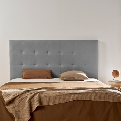 Cabeceira de cama cinzenta estofada com padrão acolchoado num quarto minimalista e luminoso